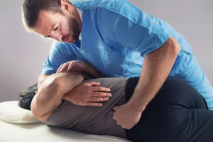 A physical therapist performing a manual adjustment on a patient's back in a clinical setting.