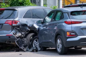 Two cars with significant damage after a rear-end collision on a city street.