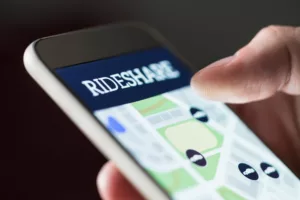 Close-up of a finger tapping on a rideshare app on a smartphone screen, indicative of the ridesharing services that can lead to accidents requiring legal assistance in Los Angeles.