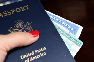 Naturalization and Citizenship 9 Close-up of a U.S. passport and a green card held by a hand with red nail polish, symbolizing the immigration services provided by the Zhanna Sanamyan Law Firm in Los Angeles.